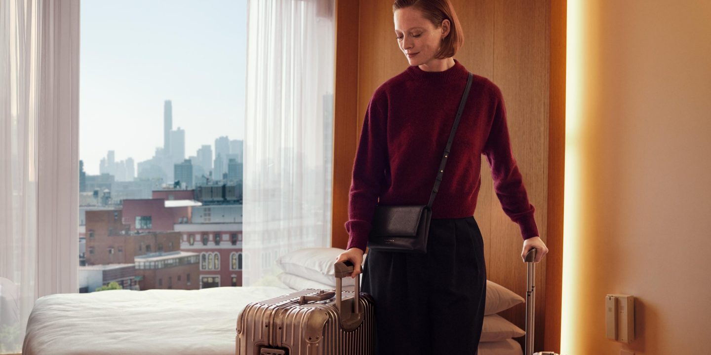 Eine Frau mit Koffer betritt ein Hotelzimmer.
