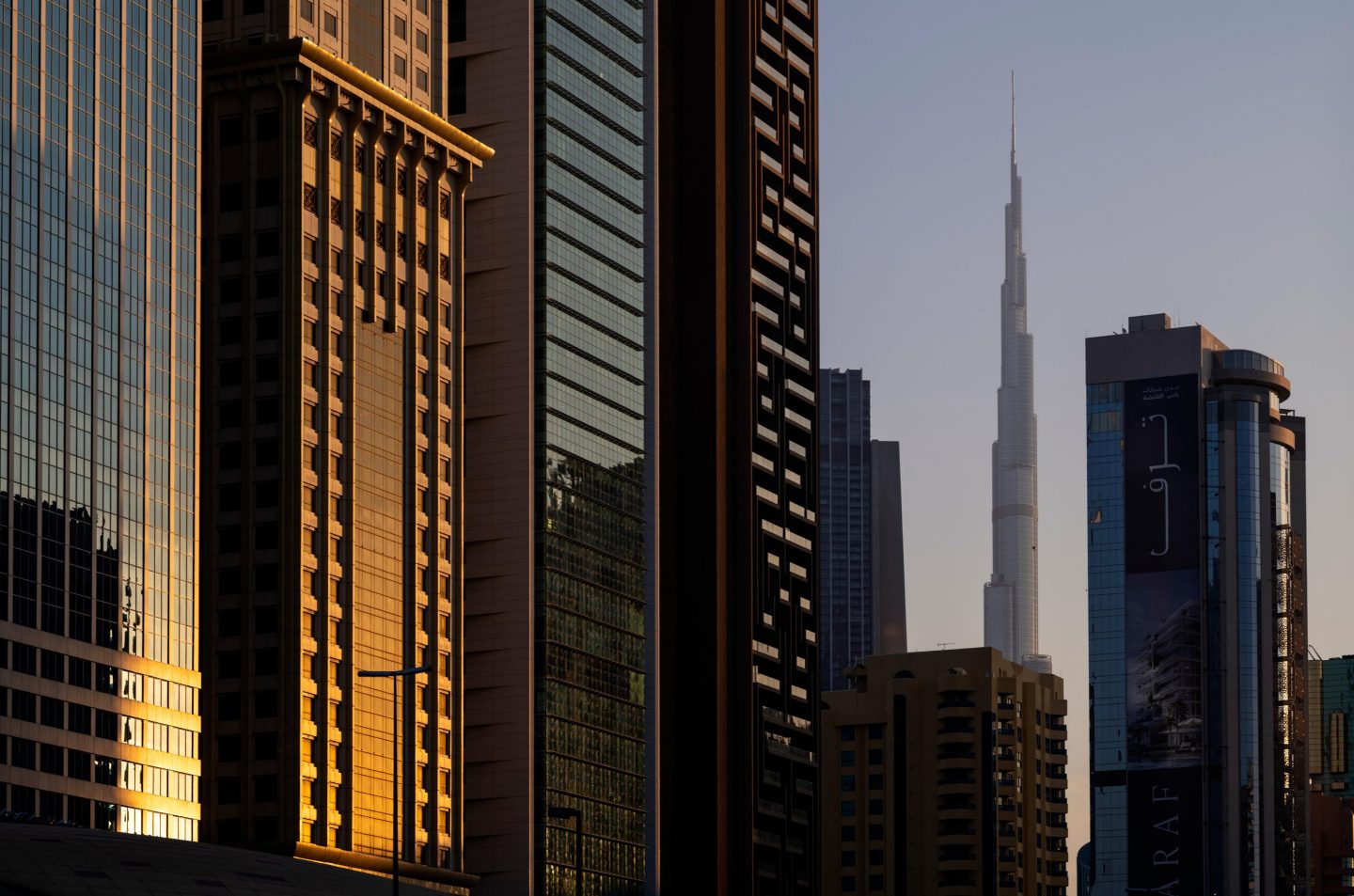 Vue de la skyline de Dubaï avec la Burj Khalifa entourée de gratte-ciel modernes au coucher du soleil.