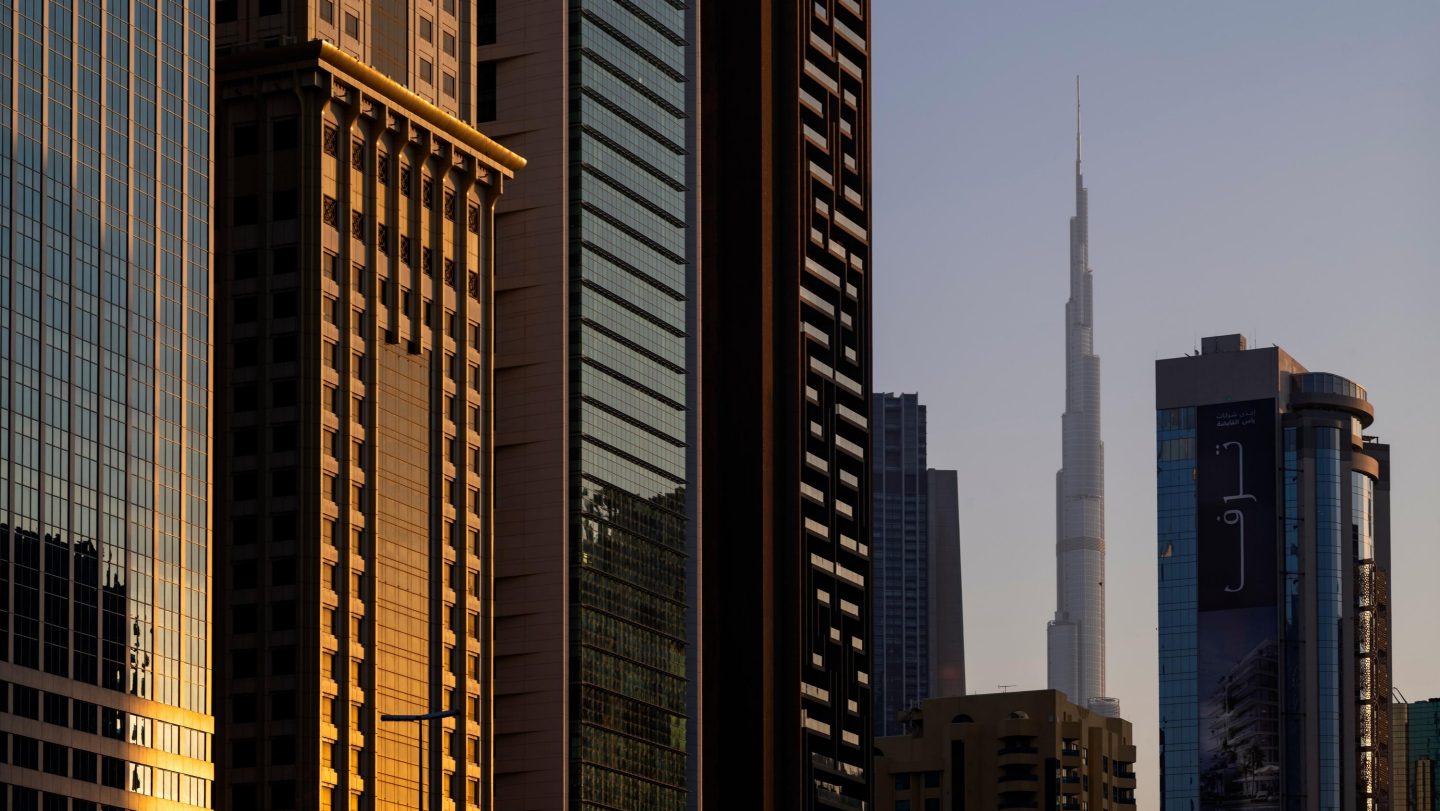 Modern Dubai skyscrapers at golden hour, with the Burj Khalifa visible in the distance.