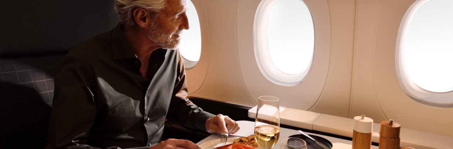 Ein Passagier der First Class genießt ein Essen am Kabinenfenster.