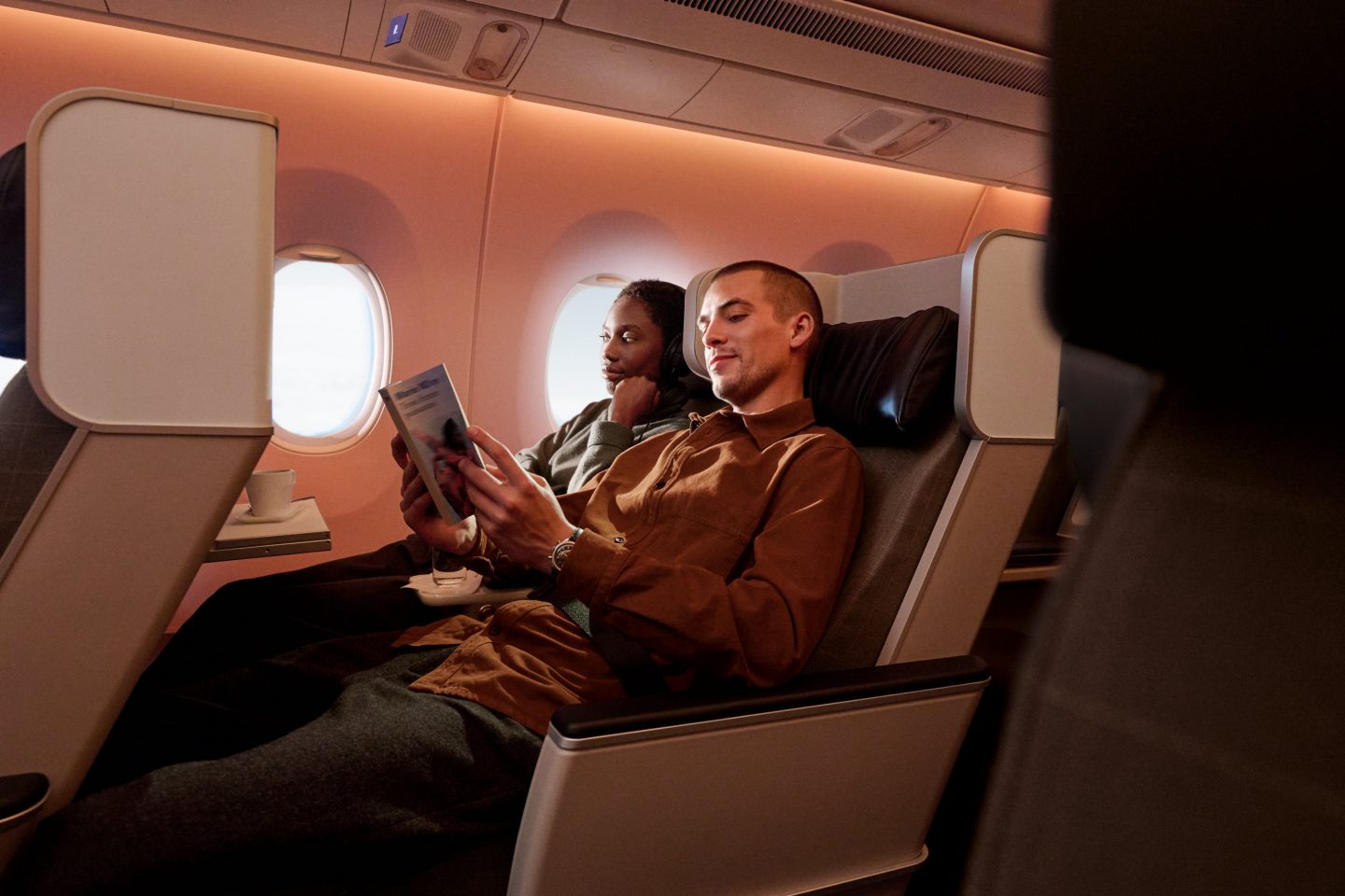A couple relaxing and reading in the comfortable seats of a modern SWISS First Class cabin.