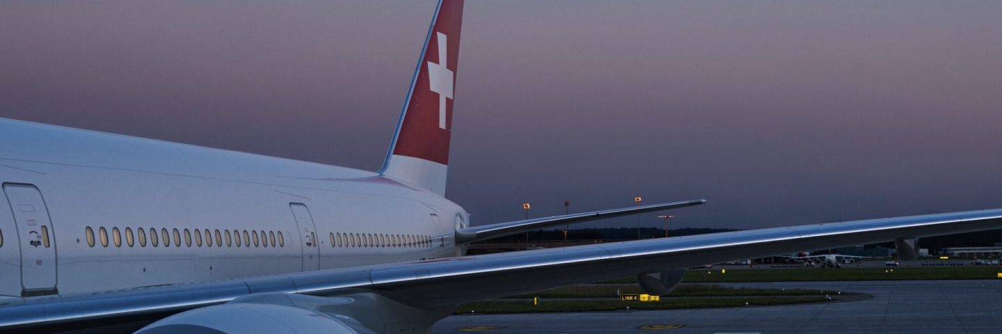 SWISS aircraft on the airport tarmac at sunset.