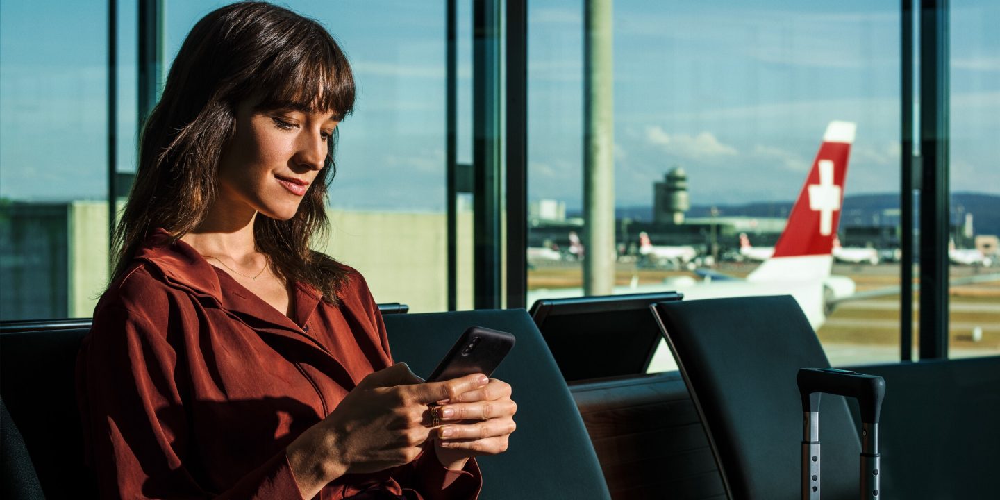 Una donna seduta in aeroporto con la pista di rullaggio sullo sfondo.