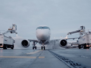 Ein SWISS Flugzeug wird von zwei Fahrzeugen enteist. 