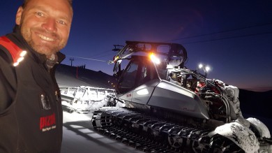 Peter Thut smiling for a selfie in front of the snow groomer. 