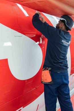 The iconic red color is carefully sprayed onto the Airbus A350, marking the beginning of the distinctive SWISS livery on the aircraft’s fuselage.