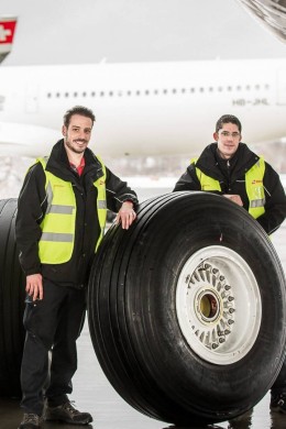 Two SWISS Technics standing next to the wheel that they have exchanged