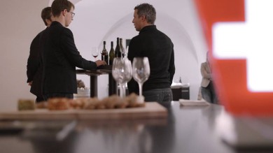 Three people standing by a table tasting wine