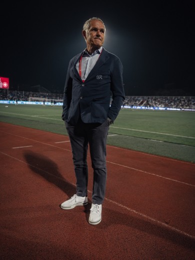 Der Direktor der Schweizer Fussball National Teams steht vor dem Spielfeld und blickt in die Ferne.