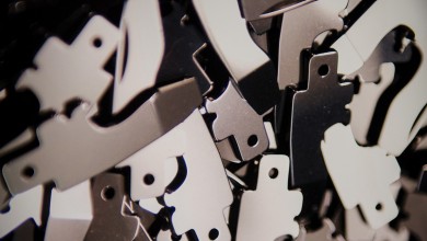 Finished pocket knife parts , which look like metallic puzzle pieces.