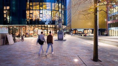 Besucher schlendern an dem HOME Theatre in der First Street vorbei, einem lebendigen Zentrum für zeitgenössisches Theater, Film, Kunst und Gastronomie im Herzen von Manchester.