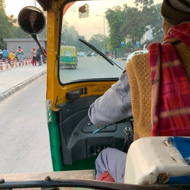 Das Bild ist aus der Beifahrerperspektive aufgenommen. Man sieht den Hinterkopf des Tuk-Tuk-Fahrers und einen kleinen Teil der Straße.