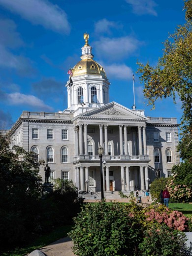 The New Hampshire State House is grey with a golden hilltop. 