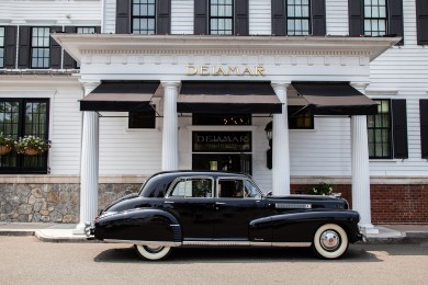 A black Cadillac Fleetwood in front of the hotel. 